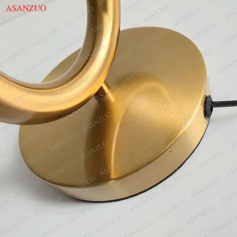 Brass-finished modern gold led u shape table lamp with sleek curved arm and circular base for bedroom art decor