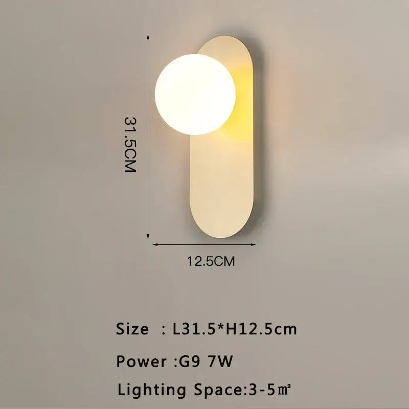 Modern gold led wall lamp with frosted glass and a warm glowing circular bulb on a matte white minimalist backplate