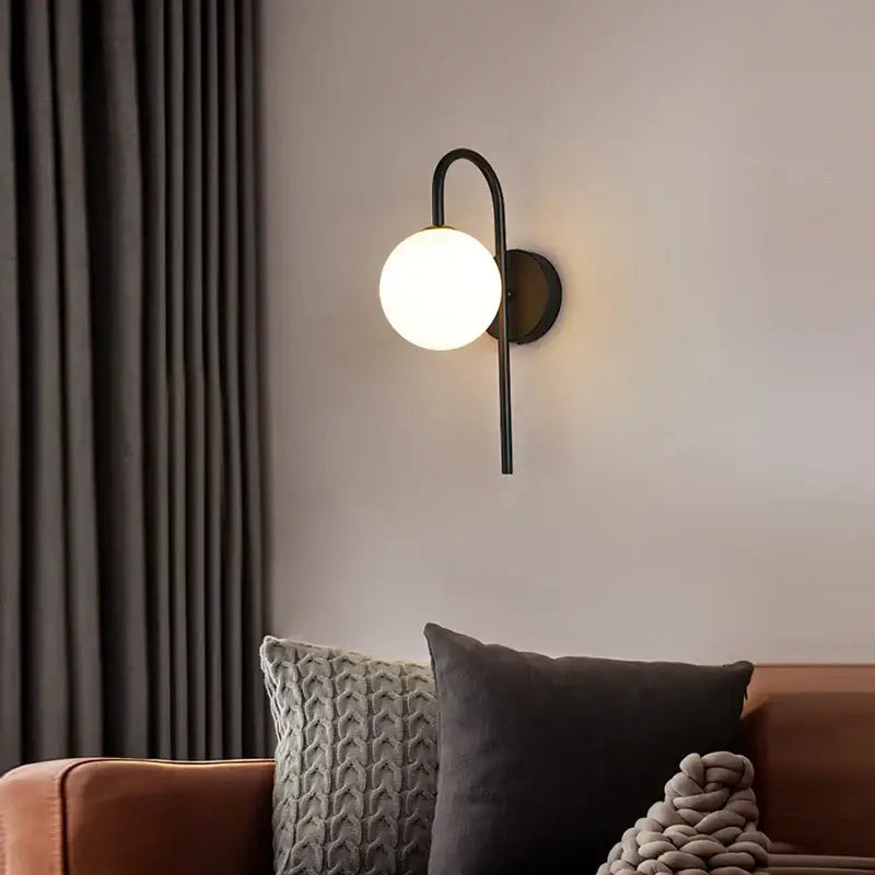 Modern black metal led wall lamp with frosted glass globe designed for elegant living room lighting