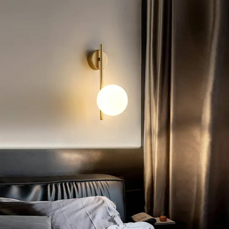 Modern gold led wall lamp featuring a gold-toned vertical rod and frosted glass globe for living room lighting