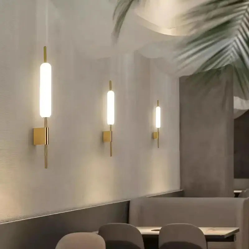 Three modern gold led wall lights with cylindrical frosted glass shades for bedroom lighting