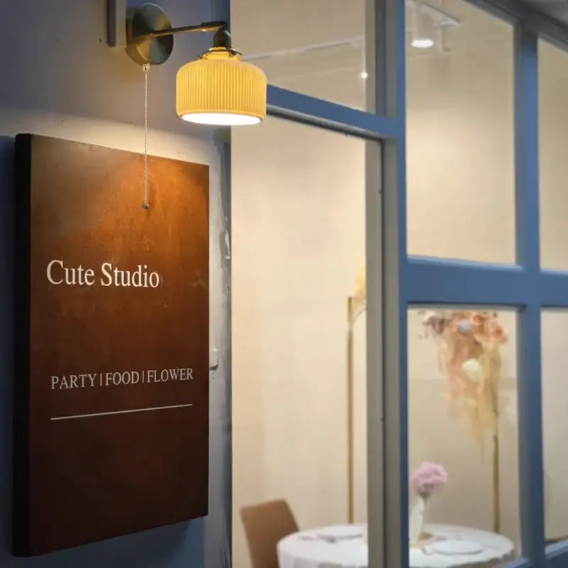A warm-toned wooden sign with white lettering displayed under modern gold led wall lights and ribbed fabric reading lamp