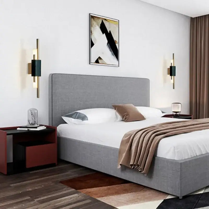 Gray upholstered bed with tufted headboard and white linens under decorbites gold led wall sconce bedroom lighting