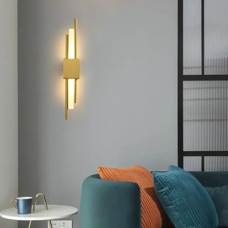 Modern gold led wall sconce with gold-toned vertical cylindrical bars and central square panel for bedroom lighting decorbites gold led wall
