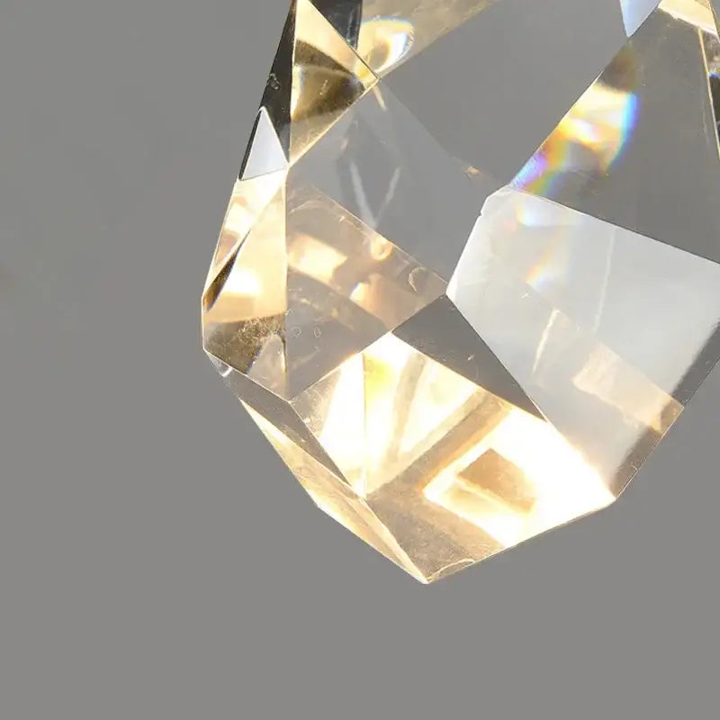 Modern gold led wall sconce with a faceted transparent crystal pendant reflecting light for living room use