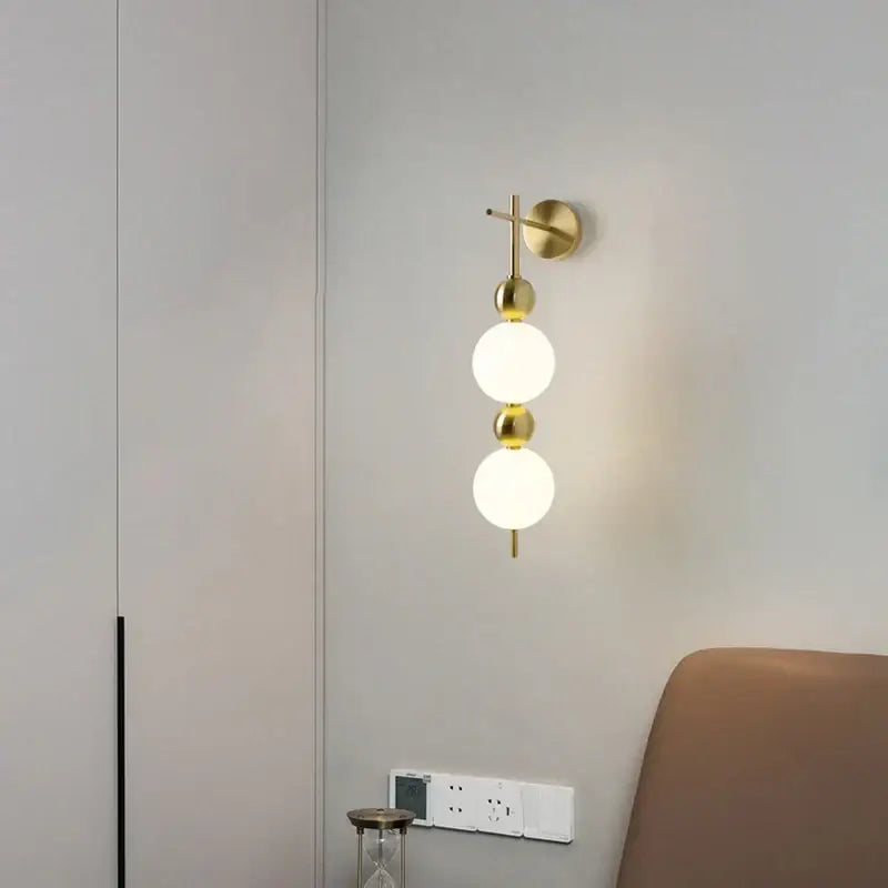 Gold-toned modern led wall sconce with frosted glass spheres and brass accents for bedroom decorbites led wall fixture