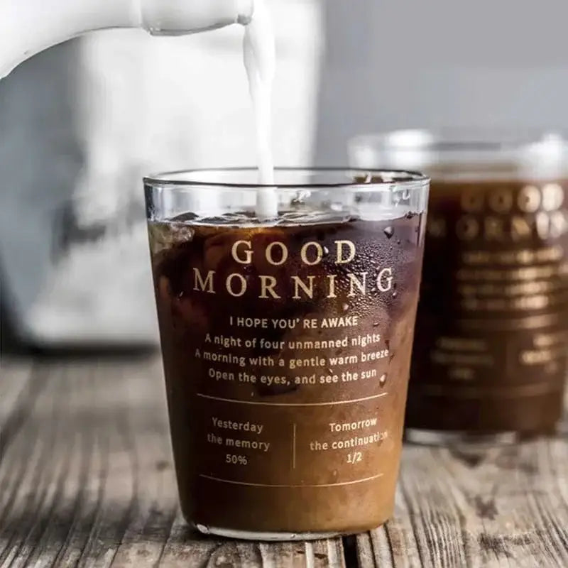 A clear glass breakfast cup with gold foil good morning text filled with iced coffee from decorbites glass breakfast