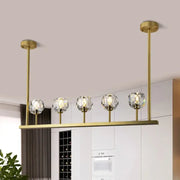 Gold-toned DecorBites 5-head linear crystal ball pendant light with five crystal globe shades for dining room ceilings