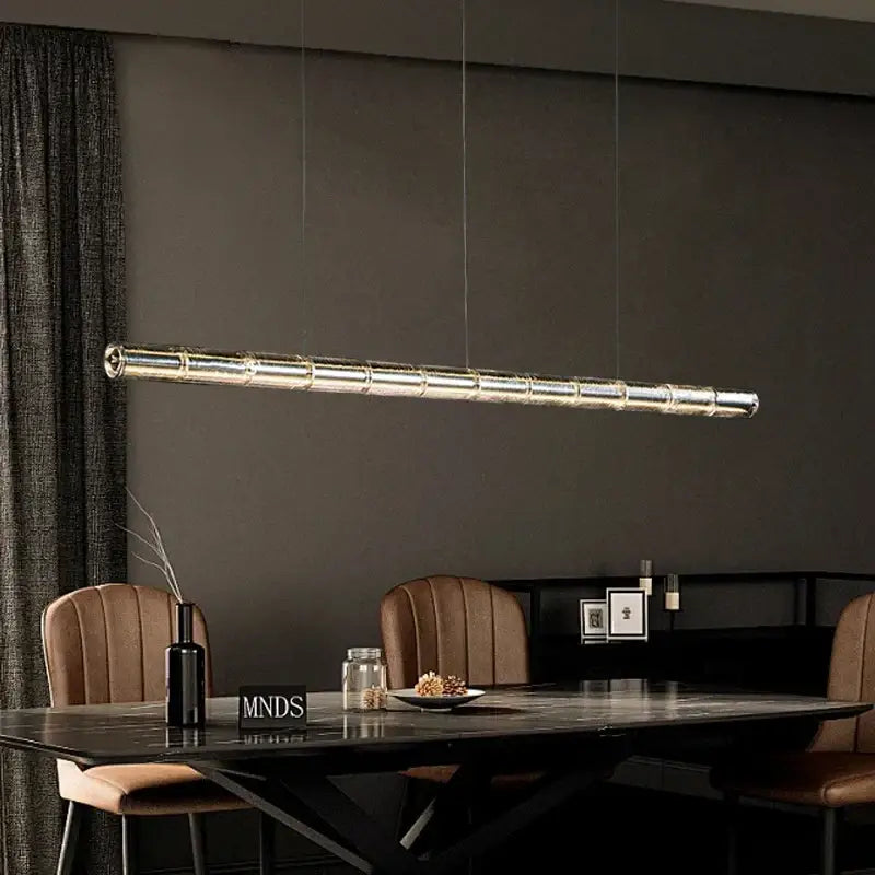 Modern gold linear glass led chandelier with segmented reflective glass panels suspended above kitchen island