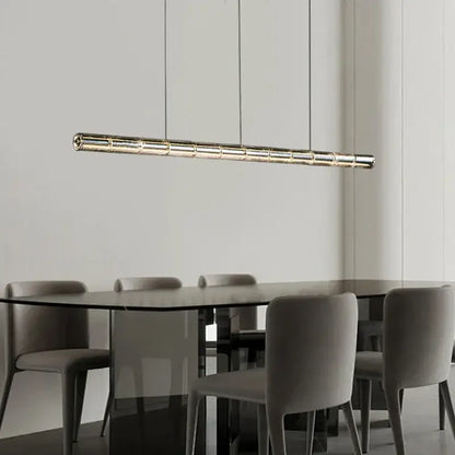 A modern gold linear glass led chandelier with a metallic finish and segmented design hangs over a kitchen island
