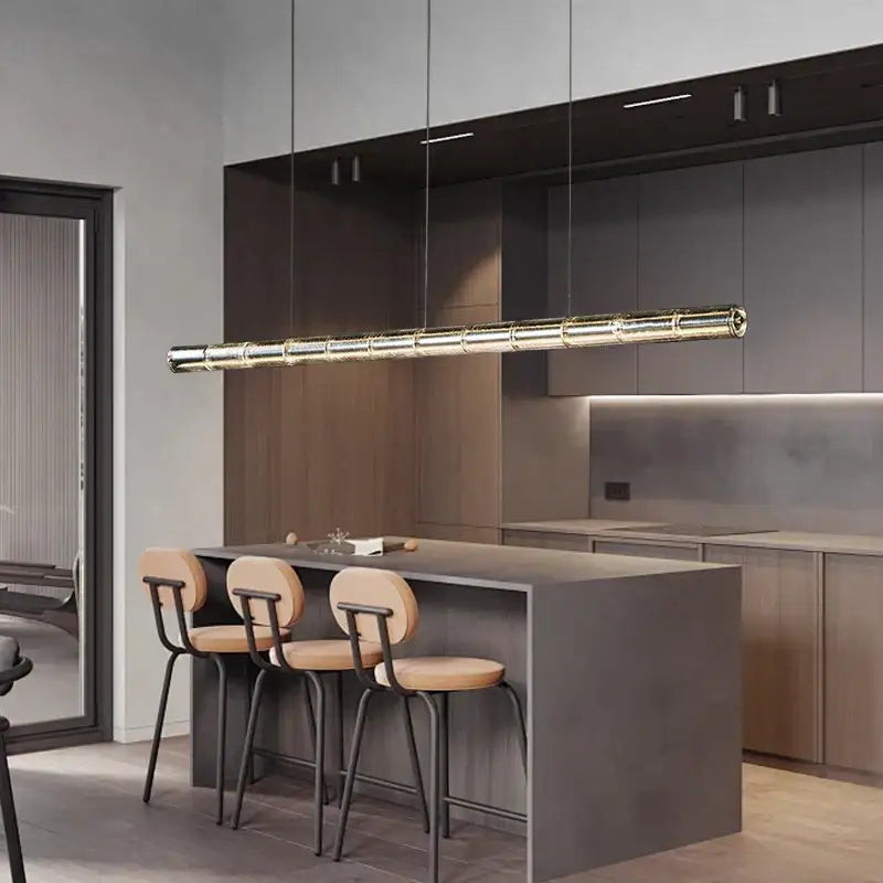 A modern gold linear glass led chandelier with a segmented metallic gold finish hangs above the kitchen island