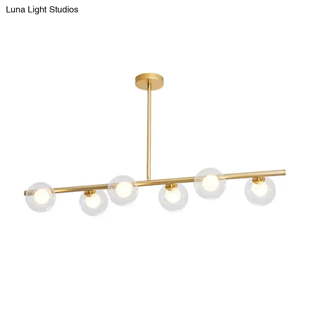Modern gold linear island light fixture with five clear glass globe shades and sleek horizontal bar design