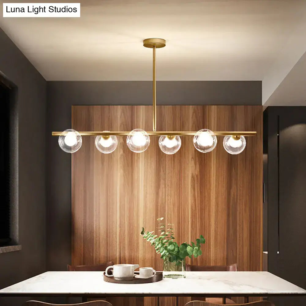 Brass-finished modern linear island light fixture with five clear glass globe bulbs for kitchen island lighting
