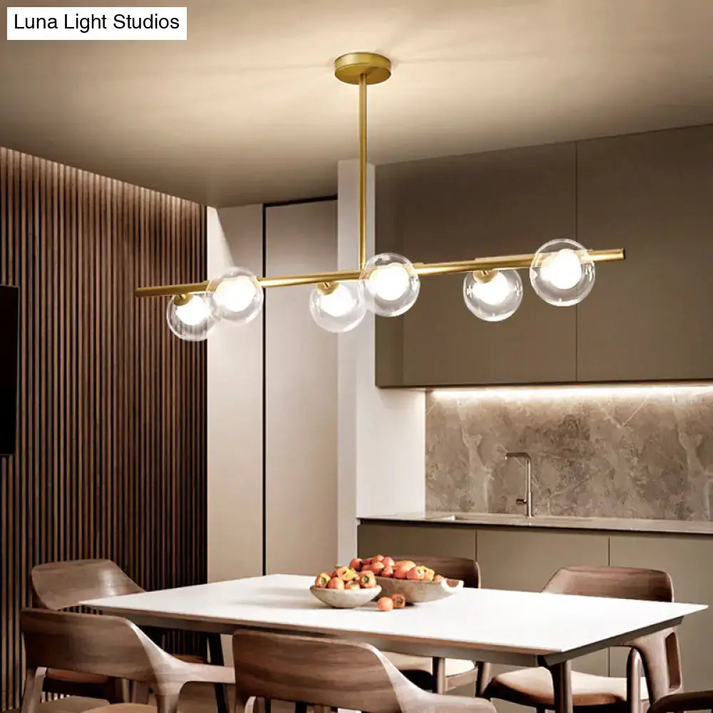 Gold-toned modern linear island light with five clear glass globe bulbs hanging from a sleek horizontal bar