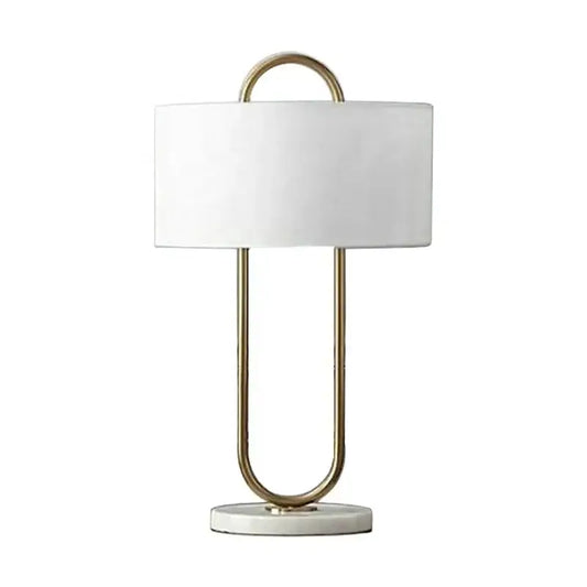 A modern gold luxury led table lamp with white cylindrical shade and u-shaped metal frame on marble base