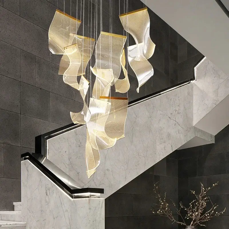 Modern gold-toned sculptural duplex building chandelier with flowing translucent panels suspended from thin cables