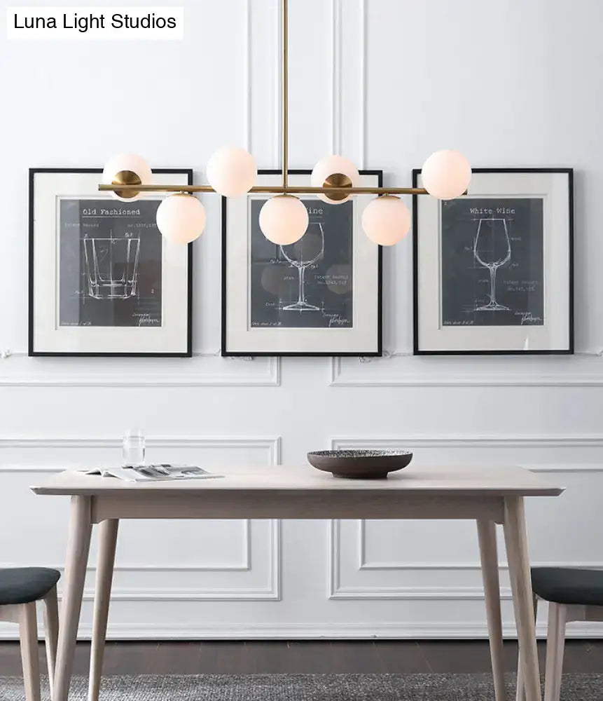 Modern gold metal chandelier with brass finish and six white glass frosted globe lights for dining room island lighting