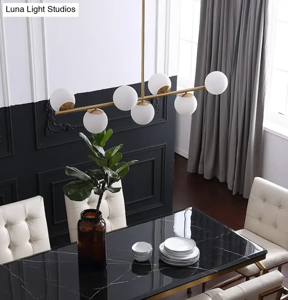 Modern gold metal island pendant with six spherical white glass globe lights for dining room lighting