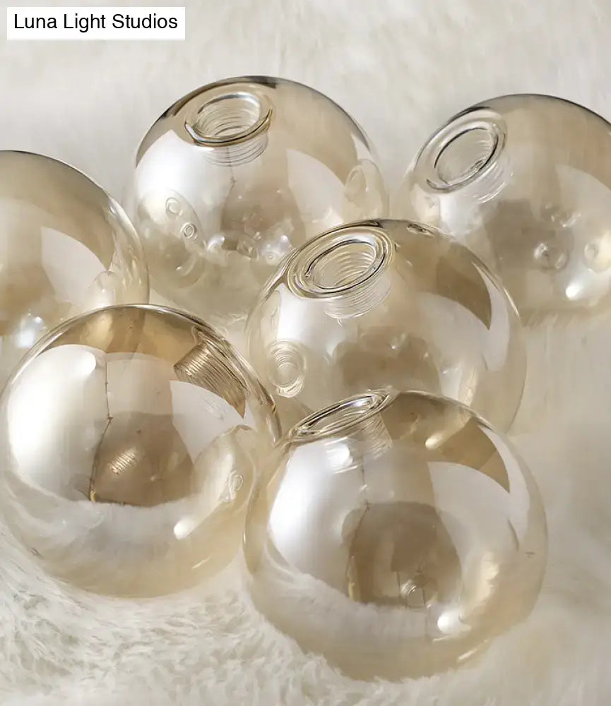 Modern gold metal amber glass island light with spherical amber glass globes and threaded tops for dining room use