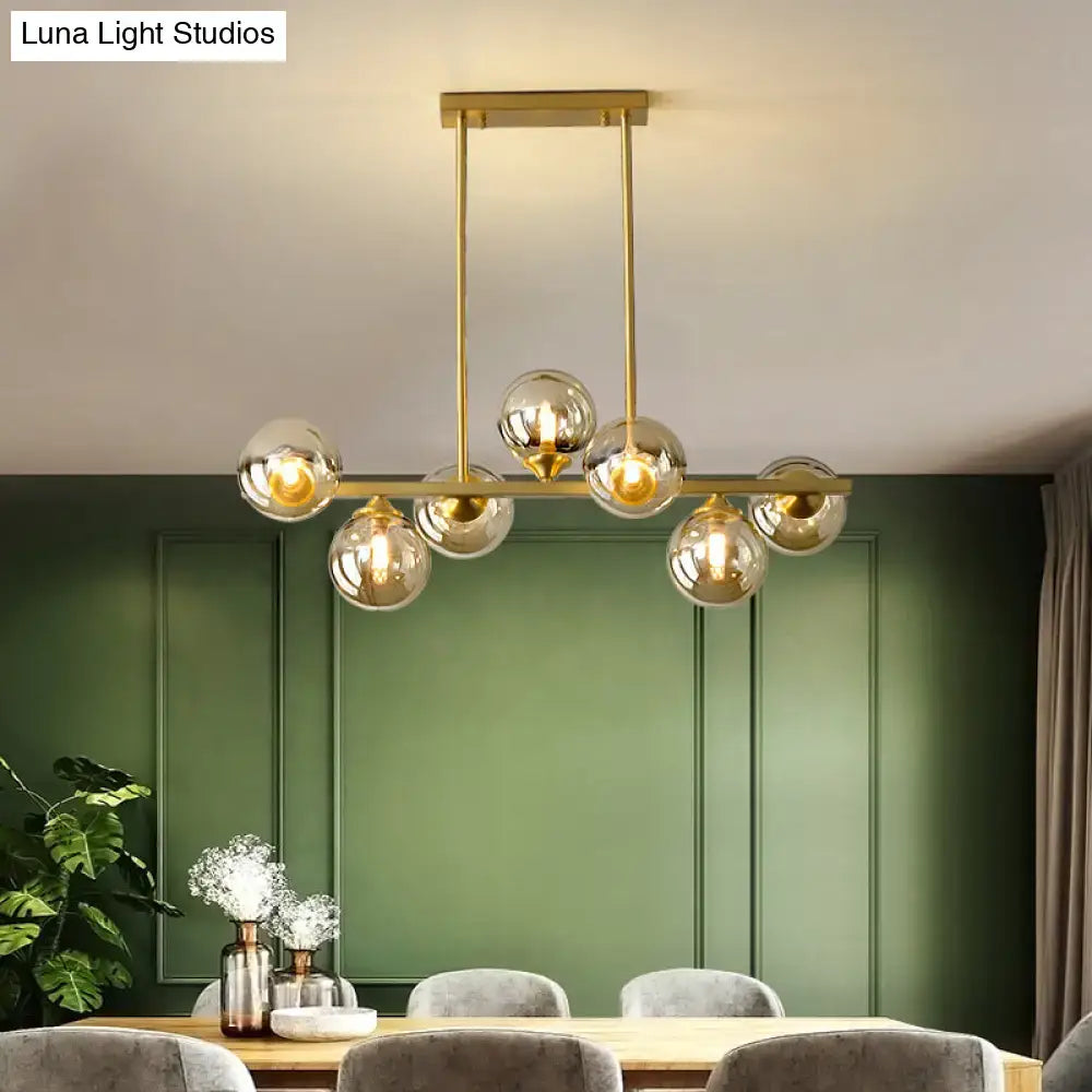 Modern gold metal chandelier with spherical amber glass globes and minimalist design for dining room island light