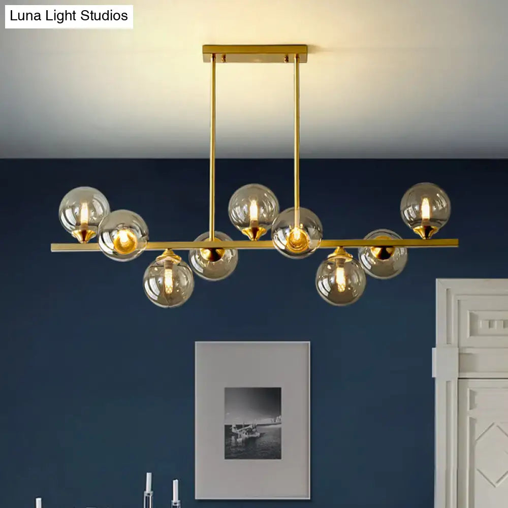 Modern gold metal island light featuring spherical amber glass bulbs suspended from a horizontal bar for dining room