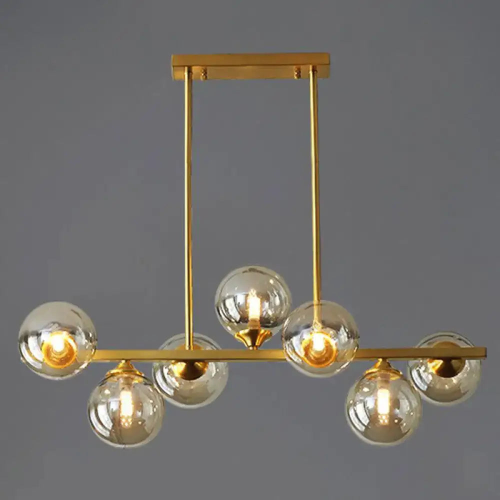 Modern gold metal island light with spherical amber glass globes and sleek horizontal bar design for dining room