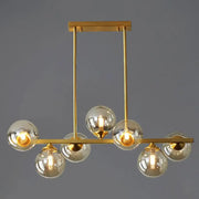 Modern gold metal island light with spherical amber glass globes and sleek horizontal bar design for dining room