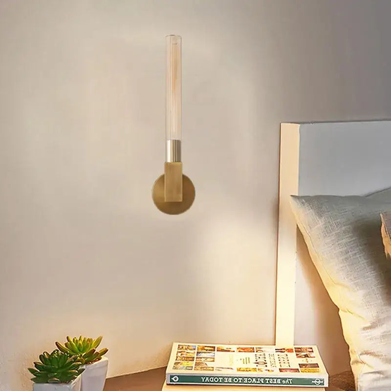 Modern gold metal and glass wall sconce light with slender translucent tube and brushed brass accents for bathroom use