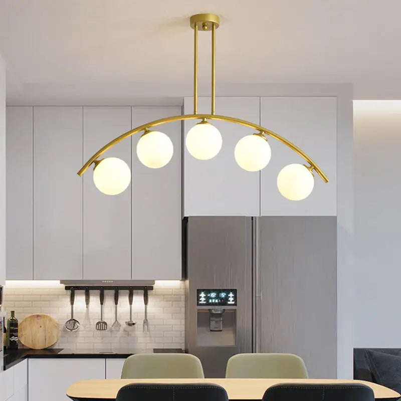 Modern gold metal arched ceiling light with five frosted glass globe bulbs for dining room illumination