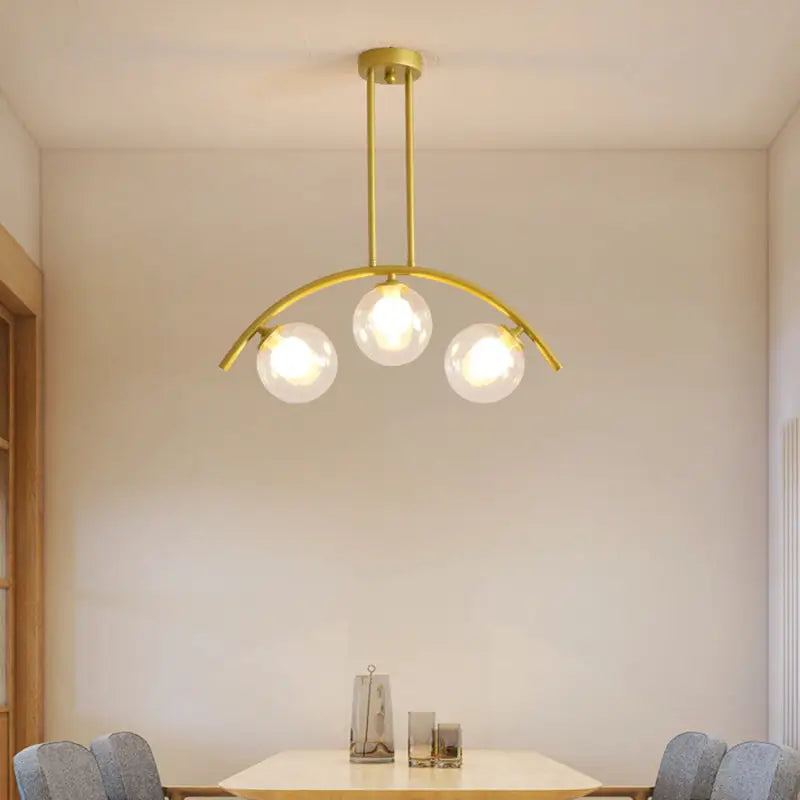 Modern gold metal arched ceiling light with three spherical glass bulbs for dining room illumination