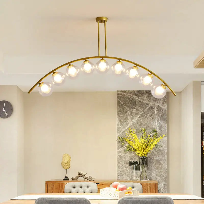Modern gold metal arched ceiling light with six spherical glass bulbs ideal for dining room illumination
