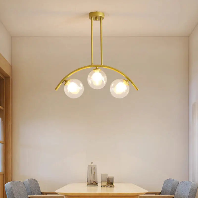 Modern gold metal arched ceiling light with three clear glass globe bulbs for dining room use