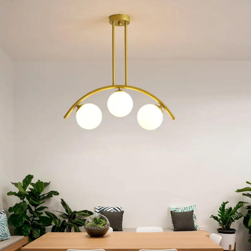 Modern gold metal arched ceiling light with three spherical frosted glass bulbs for dining room use