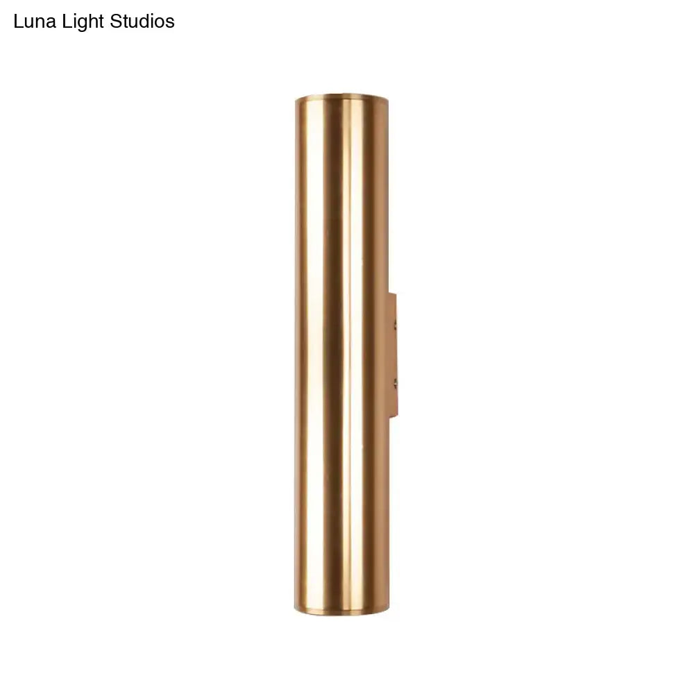 A sleek cylindrical brass wall lamp with a minimalist design and polished finish metal fixture for corridor use