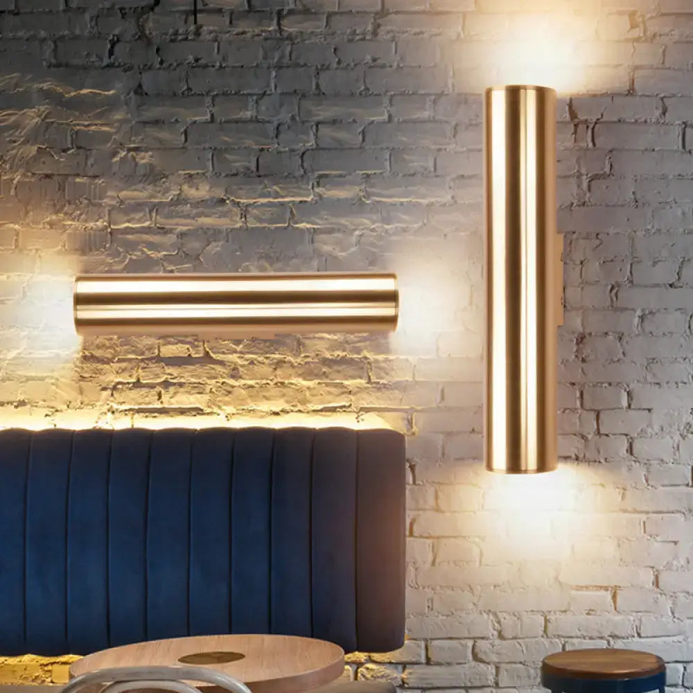 Two sleek cylindrical brass metal fixture wall lamps in gold designed for modern corridor lighting