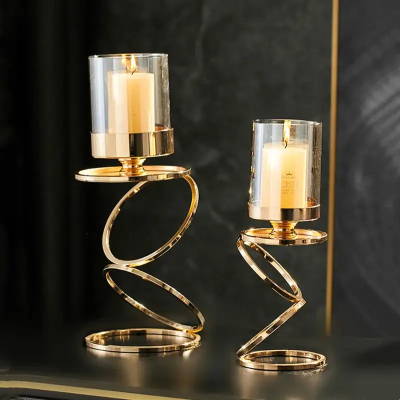 Modern gold metal frame candle holder with gold-toned spiral design and glass cups holding lit cream candles centerpiece