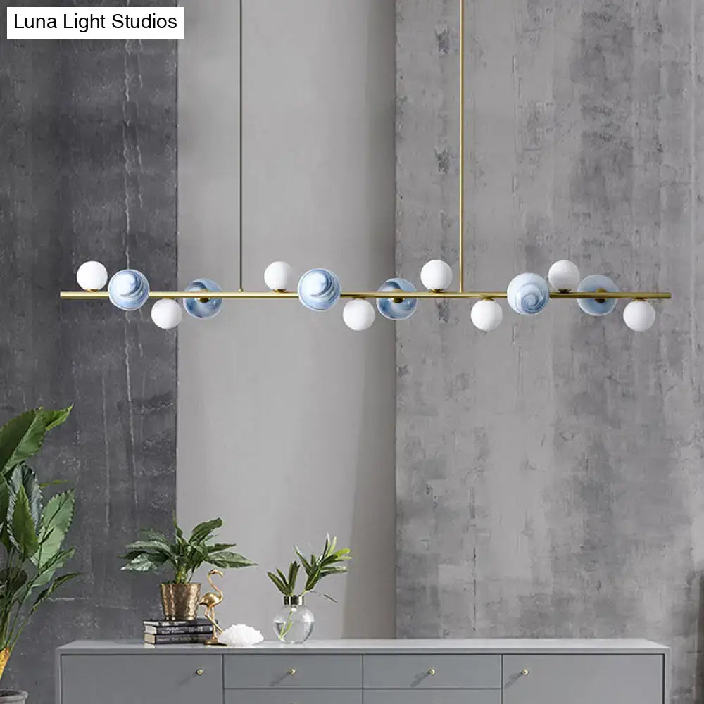 Modern gold metal glass globe chandelier with brass frame and chain cord length featuring blue and white spheres above dining table