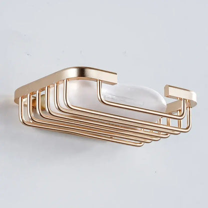 Modern gold-toned metal soap dish with sleek parallel bars and rounded edges for wall mounted glass soap use