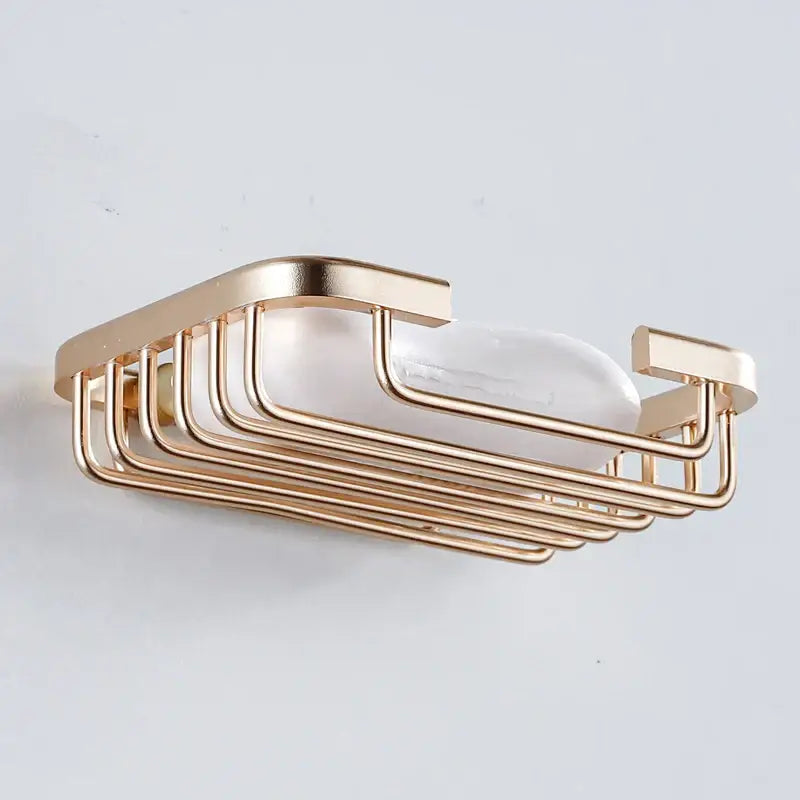 Modern gold-toned metal soap dish with sleek parallel bars and rounded edges for wall mounted glass soap use