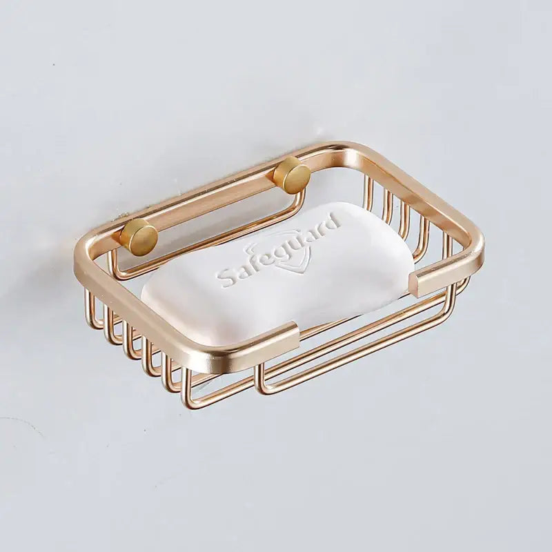 Modern gold-toned metal soap dish with sleek wireframe design holding a white safeguard bar of soap for bathroom use
