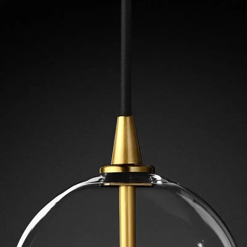 Modern gold metal globe pendant light with a clear glass dome and polished brass decorbites gold metal hardware
