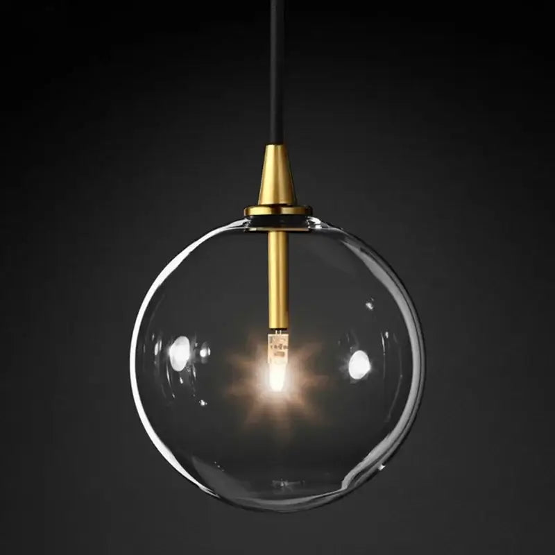 A modern gold metal globe pendant light with a brass fixture and black cord for dining room decorbites decor