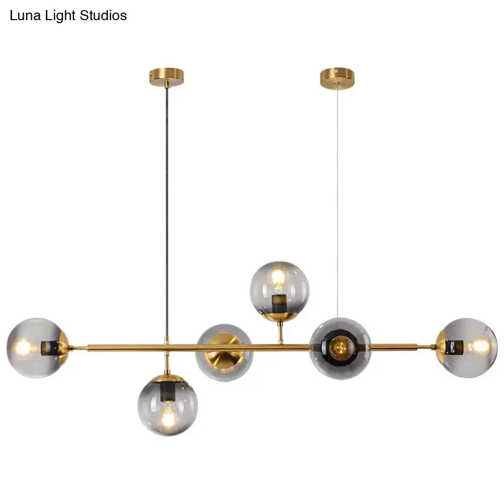 Modern gold metal island pendant chandelier with six brass and smoked glass globe bulbs for dining room lighting
