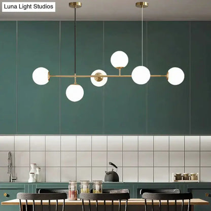 Modern gold metal island pendant with five frosted glass globe bulbs and blue glass spheres for dining rooms