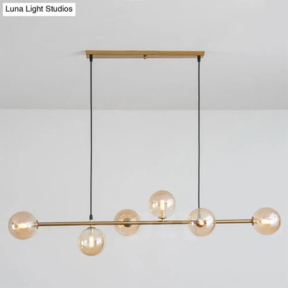 Modern gold metal island pendant featuring five amber glass globes with brass and blue glass accents for dining rooms