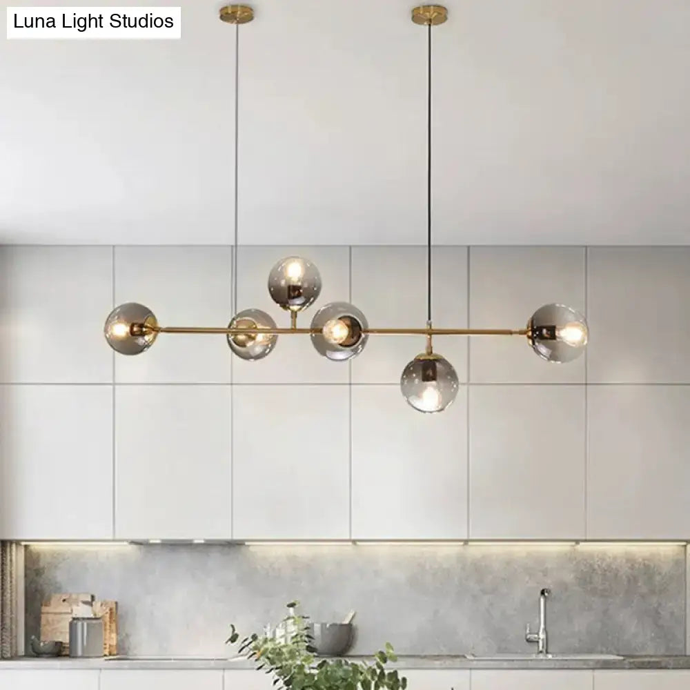 Modern gold metal island pendant with five smoked glass globes suspended by thin cords for dining room lighting