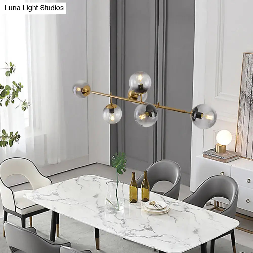 Modern gold metal island pendant with linear design and clear glass globe bulbs for dining room lighting