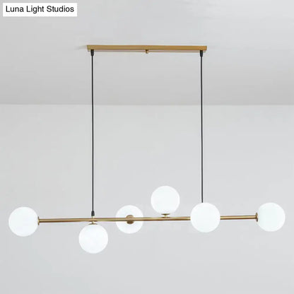 Modern gold metal island pendant with five frosted glass globes and black cords for dining room lighting