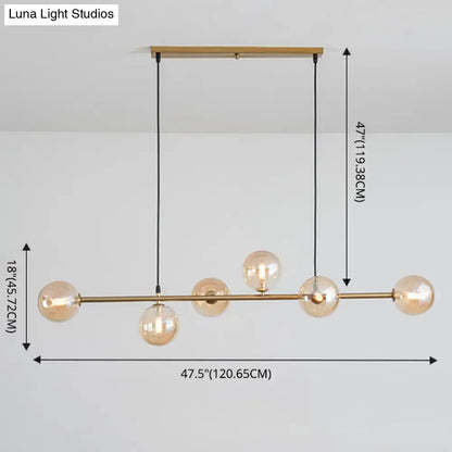 Modern gold metal island pendant with five amber glass bulbs and black cords suspended from wooden ceiling mount