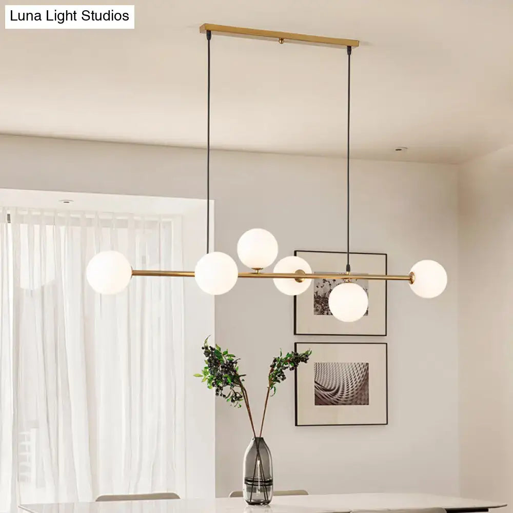 Modern gold metal island pendant with five frosted glass globe bulbs and blue glass spheres for dining room lighting